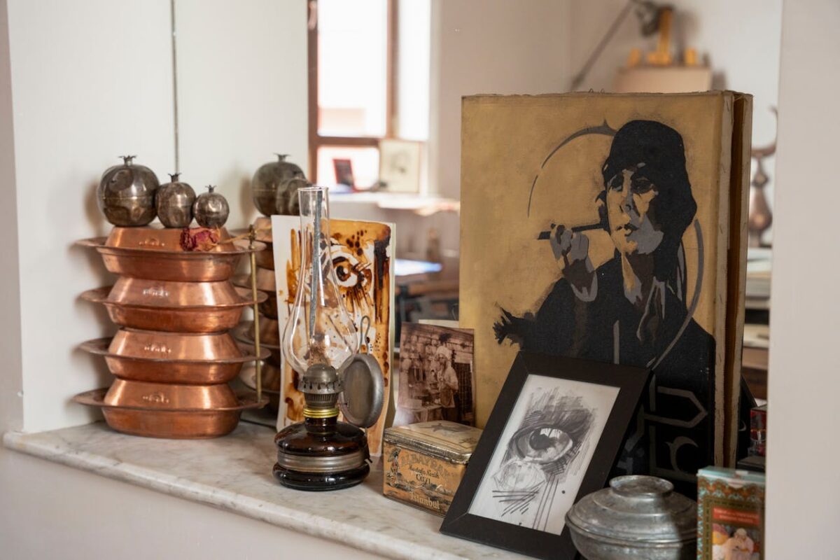A collection of vintage home decor items including copperware, an antique oil lamp, and vintage art in a cozy indoor setting.